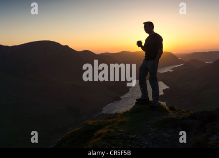 Un uomo riflette sui giorni eventi mentre si beve una calda tazza di tè sul vertice di Fleetwith Pike. Foto Stock