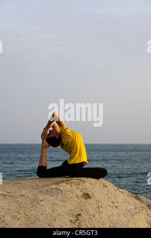 La donna in una posizione di yoga, Kapotasana, dal mare in Kanyakumari, Tamil Nadu, India, Asia Foto Stock