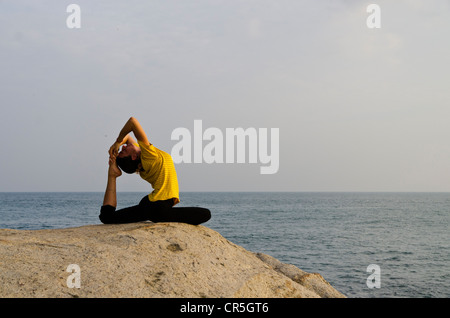 La donna in una posizione di yoga, Kapotasana, dal mare in Kanyakumari, Tamil Nadu, India, Asia Foto Stock