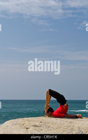 La donna in una posizione di yoga, Salabhasana, dal mare in Kanyakumari, Tamil Nadu, India, Asia Foto Stock