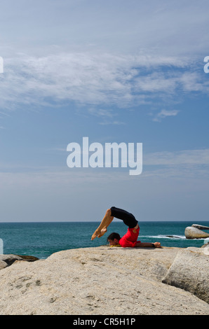 La donna in una posizione di yoga, Salabhasana, dal mare in Kanyakumari, Tamil Nadu, India, Asia Foto Stock