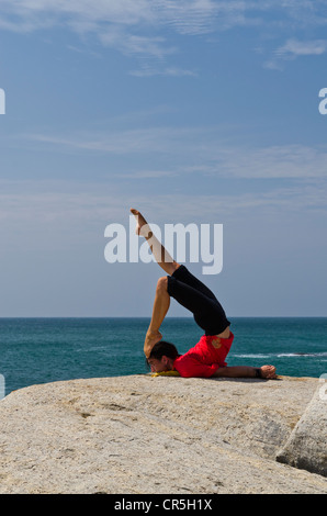 La donna in una posizione di yoga, Salabhasana, dal mare in Kanyakumari, Tamil Nadu, India, Asia Foto Stock