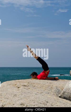 La donna in una posizione di yoga, Salabhasana, dal mare in Kanyakumari, Tamil Nadu, India, Asia Foto Stock