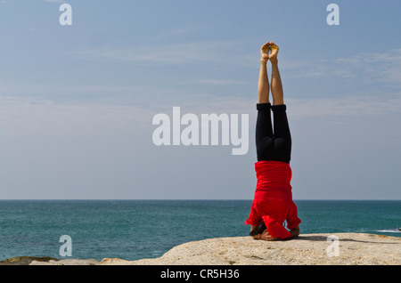 La donna in una posizione di yoga, Sirshasana, dal mare in Kanyakumari, Tamil Nadu, India, Asia Foto Stock