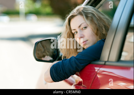 Giovane donna che guarda fuori dalla finestra di una automobile Foto Stock