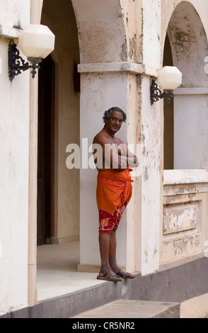 Uomo in arancione sarong esterno bianco casa coloniale sulla Forte Galle's Peddler Street, Galle, Southern, Sri Lanka Foto Stock
