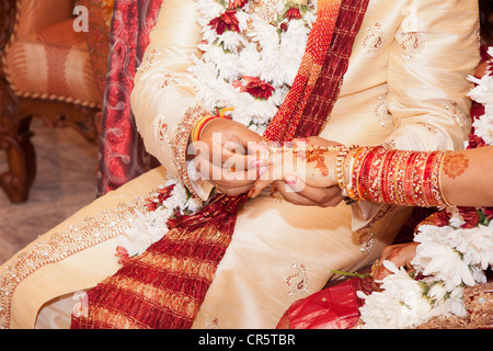 Indian groom passando l'anello nuziale sulla sua sposa del dito Foto Stock