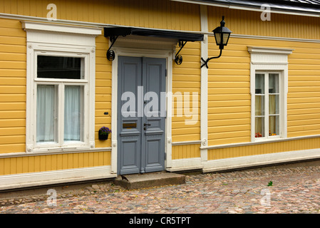 Ocra Gialla facciata di un finlandese tradizionale casa di registro con finestre e porta di ingresso, la città vecchia di Porvoo, Finlandia, Europa Foto Stock