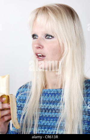 Donna bionda di mangiare una banana Foto Stock