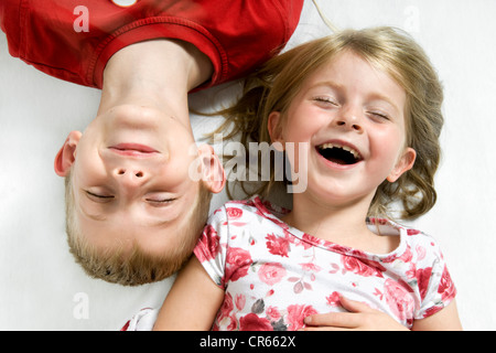Due bambini caucasici, un fratello e una sorella avendo divertimento (7 anno vecchia ragazza e 8 anno old boy) su uno sfondo bianco Foto Stock