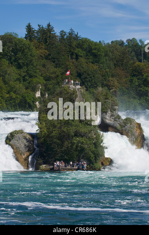 Roccia nel fragore acque delle cascate del Reno di Sciaffusa, i turisti al molo e sulla cima della roccia, Svizzera Foto Stock