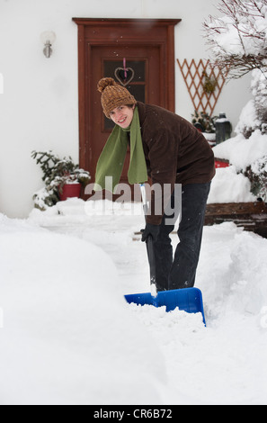 Austria, giovane spalare la neve davanti la casa, ritratto Foto Stock