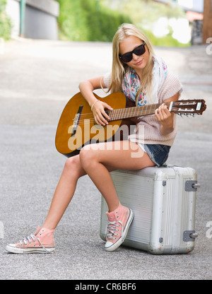 Austria, ragazza adolescente con Borsoni con ruote e suonare la chitarra Foto Stock