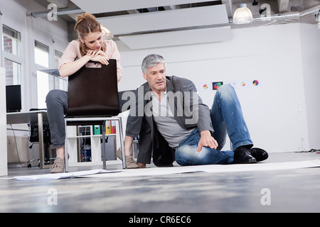 In Germania, in Baviera, Monaco di Baviera, uomo spiegando piano per donna in ufficio Foto Stock