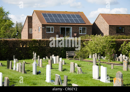 Pannello solare / pannelli su un tetto di casa / casa tetti e un cimitero con tombe / grave pietre. Wareham. Il Dorset. Regno Unito. Foto Stock