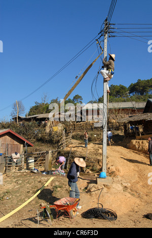Laos , villaggio hmong Nam Kha , elettrificazione del villaggio da lao-società tedesca Sunlabob e ONG, lavoratore facendo il cablaggio nel polo di alimentazione per una off-dio net nel villaggio, il potere è prodotto dalla piccola turbina idraulica Foto Stock