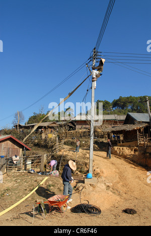 Laos , villaggio hmong Nam Kha , elettrificazione del villaggio da lao-società tedesca Sunlabob e ONG, lavoratore nel polo di alimentazione facendo il cablaggio di un off-grid rete elettrica, l'energia proviene dal piccolo idro turbina Foto Stock