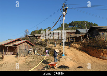 Laos , villaggio hmong Nam Kha , elettrificazione del villaggio da lao-società tedesca Sunlabob e ONG, lavoratore facendo il cablaggio nel polo di alimentazione per una off-dio net nel villaggio, il potere è prodotto dalla piccola turbina idraulica Foto Stock