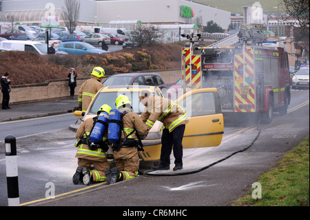 I vigili del fuoco di mettere fuori un auto a motore fire su una strada trafficata in Brighton Foto Stock
