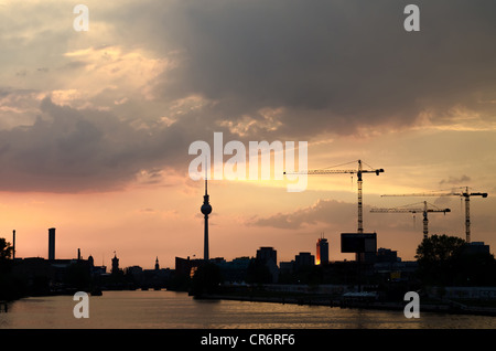 Skyline di Berlino al tramonto con gru per edilizia Foto Stock