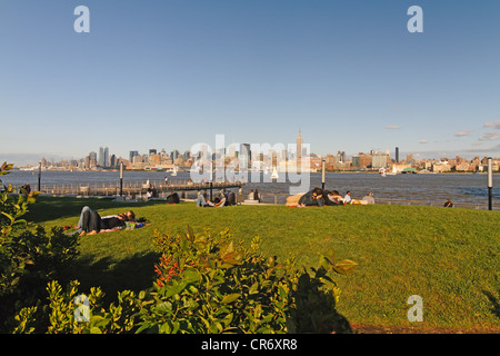 Persone rilassarsi sul prato del molo C Park di Hoboken con lo skyline di Manhattan in background, New Jersey Foto Stock