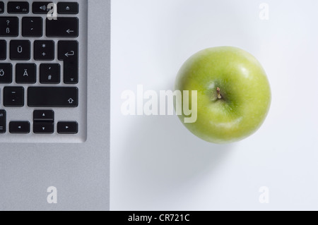 Laptop e mela verde su sfondo bianco Foto Stock