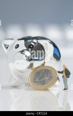 Figurina maschio toccando euro moneta oltre a salvadanaio su sfondo bianco Foto Stock