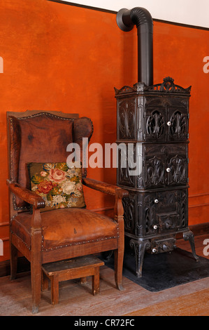 Fauteuil sedia e in ghisa stufa, 1900, soggiorno in cucina a casa dell'insegnante, edificio scolastico da Pfaffenhofen Foto Stock