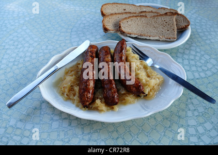 Tre della Franconia salsicce bratwurst con crauti e il pane su una piastra su un tavolo di osteria, Ratisbona, Alta Franconia, Bavaria Foto Stock