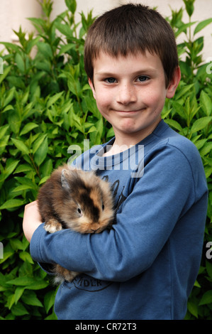 Il ragazzo, 6 anni, tenendo il suo coniglio in sue braccia con orgoglio Foto Stock