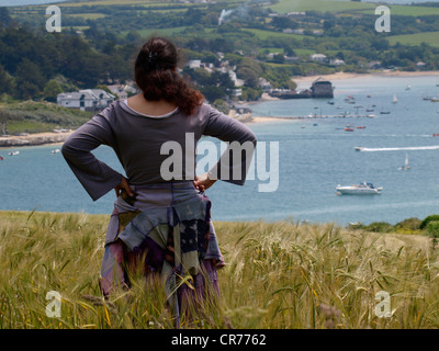 Donna in piedi in un campo di mais guardando la vista, Padstow, Cornwall, Regno Unito Foto Stock