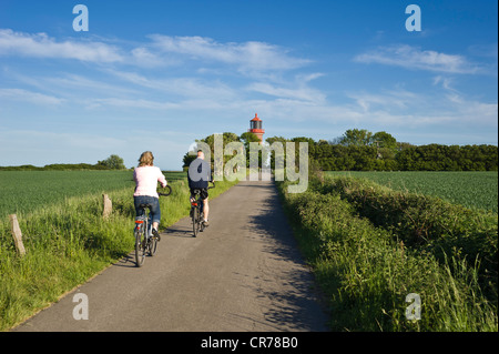 I ciclisti nella parte anteriore del faro sulle rupi costiere di Staberhuk, Fehmarn Island, Mar Baltico, Schleswig-Holstein Foto Stock