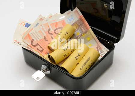 Le banconote in euro e arrotolato a monete in una cassa Foto Stock