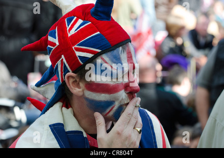 L'uomo con la bandiera dell'Unione faccia fumi di verniciatura il diamante della regina celebrazioni giubilari di festeggianti in attesa di pop concert in The Mall Foto Stock