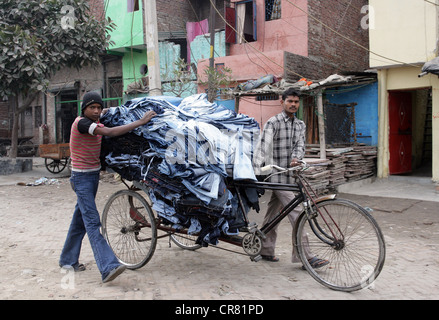 In rickshaw come trasportatore di un paio di jeans sartoria nella baraccopoli Janata Colony a Nuova Delhi, India Foto Stock