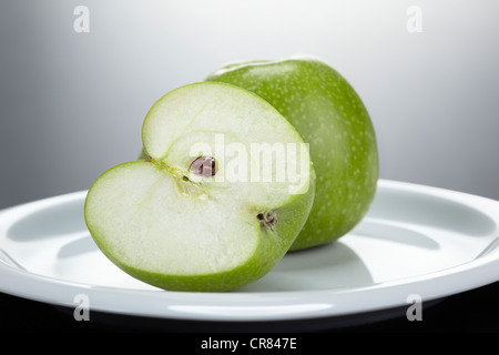 Due verdi le mele Granny Smith, un taglio aperto su una piastra bianca Foto Stock