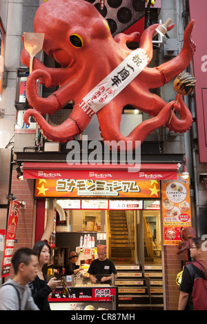 Cucina di strada venditore, vendita takoyaki polpo palle, nel quartiere dei divertimenti di Dotonbori, in Osaka, la regione di Kansai, Giappone. Foto Stock