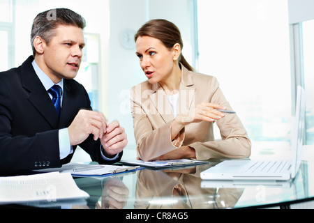 Formalmente vestiti giovani tenendo una discussione in office Foto Stock