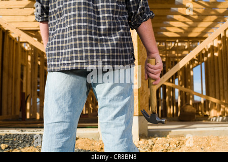 Uomo con martello nella parte anteriore del telaio della nuova casa Foto Stock