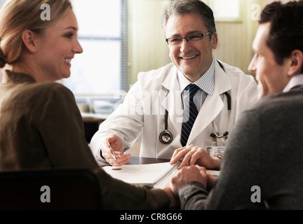 Coppia giovane nell'ufficio del medico ricevendo buone notizie Foto Stock