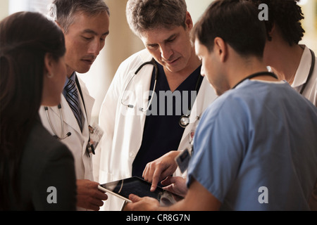 I medici a discutere di pazienti grafici sulla tavoletta digitale in ospedale Foto Stock