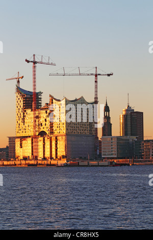 Elbe Philharmonic Hall building site al tramonto sulla Kehrwiederspitze sul fiume Elba, con la HTC Hanseatic Trade Center Foto Stock