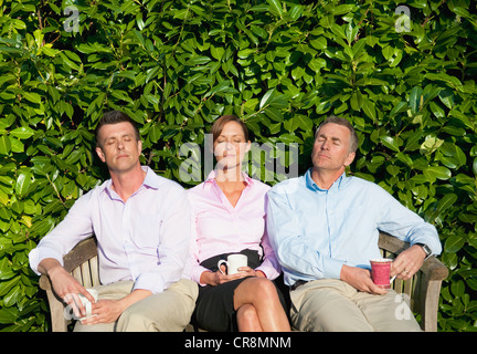 Tre imprenditori seduta sul banco, addormentato Foto Stock