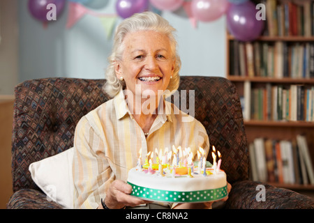 Senior donna holding torta di compleanno, ritratto Foto Stock