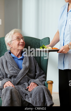 Accompagnatore portando pasto uomo senior Foto Stock