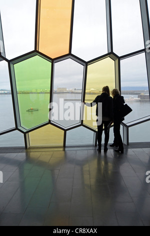 I visitatori che desiderano attraverso il conformate a nido d'ape finestre nella facciata, new Harpa concert hall a Reykjavik, Islanda, Europa Foto Stock