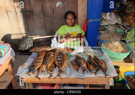 Donna di Papua la vendita di pesce fritto al mercato del pesce in Kota Biak, salutando il vola con un sacchetto di plastica su un bastone Foto Stock