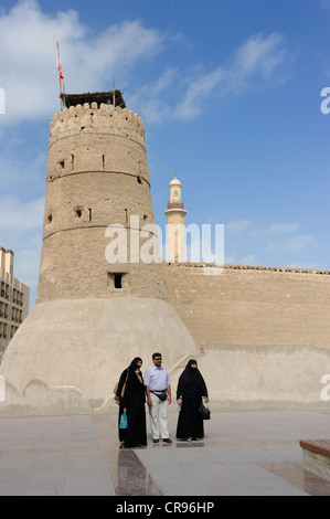 Uomo arabo con le mogli in piedi di fronte alla torre della fortezza di Dubai, il museo di Dubai, Emirati Arabi Uniti, Arabia Foto Stock