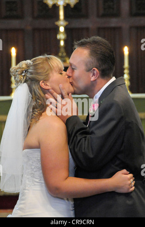 Close up della sposa e sposi primo bacio durante una cerimonia religiosa in una chiesa Cookham. Foto Stock