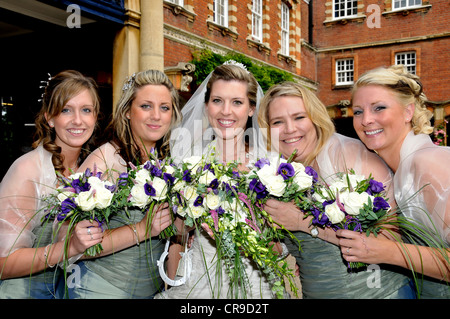 Sorridente e sposa la sua brides cameriere in stretta group holding il loro bouquet. Foto Stock